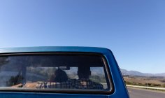 Rear view of a couple driving in a pick-up truck on a highway during a road trip, seen through the truck rear window — Stock Photo