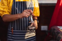 Vista frontal seção média da mulher vestindo um avental preparando café em um caminhão de venda de alimentos — Fotografia de Stock
