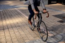 Вид спереду низька частина чоловіка, що їде на велосипеді на міській вулиці. Цифровий кочівник на ходу . — стокове фото