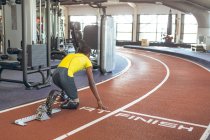 Заднього виду інвалідів афро-американських чоловіків атлетичні на стартовому блоці на бігові доріжки в фітнес-центр — стокове фото