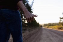 Low section of man hitchhiking on the road — Stock Photo