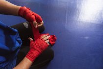 Visão aérea seção baixa de boxeador masculino em um anel de boxe envolvendo suas mãos — Fotografia de Stock