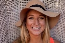 Ritratto di una giovane donna caucasica felice che si rilassa in vacanza, indossa un cappello e sorride alla telecamera — Foto stock
