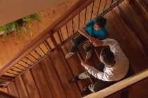 Visão aérea de um homem caucasiano de meia-idade comemorando com um soco no punho com seu filho pré-adolescente sentado em uma escada — Fotografia de Stock