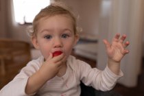 Portrait of a Caucasian baby eating a strawberry — Stock Photo