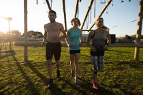 Front view of two young Caucasian women and a young Caucasian man running at an outdoor gym during a bootcamp training session — Stock Photo