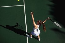 Vista ad angolo alto di una giovane donna caucasica che gioca a tennis in una giornata di sole, servendo — Foto stock