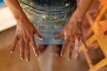 Elevated close up of the hands of female potter with clay on them in a pottery studio — Stock Photo
