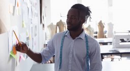 Front view of a young African American male fashion student standing working in a studio at fashion college — Stock Photo