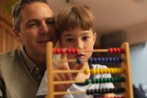 Front view close up of a middle aged Caucasian man helping his pre teen son to use abacus — Stock Photo