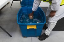 Visão lateral seção baixa do trabalhador da fábrica inspecionando uma caixa de plástico azul de líquido — Fotografia de Stock