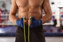 Visão frontal seção média do boxeador masculino segurando uma corda pulando em um ginásio de boxe — Fotografia de Stock