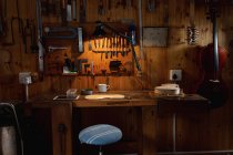 Violon fabriqué dans un atelier luthier avec des outils accrochés au mur en arrière-plan — Photo de stock
