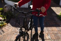 Frente vista mulher segurando uma bicicleta — Fotografia de Stock