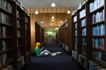 Бічний вид на молоду азіатську студентку, яка носить хіджаб за допомогою смартфона і навчається в бібліотеці — стокове фото