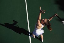 Hochwinkelaufnahme einer jungen kaukasischen Frau, die an einem sonnigen Tag Tennis spielt und — Stockfoto