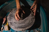 Elevato primo piano delle mani di vasaio femminile plasmare argilla su una ruota vasai in uno studio di ceramica — Foto stock