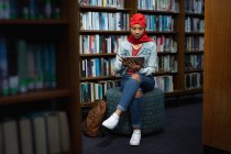 Visão frontal de uma jovem estudante asiática vestindo um turbante usando um computador tablet e estudando em uma biblioteca — Fotografia de Stock