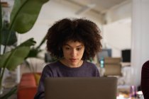 Nahaufnahme einer jungen Frau mit gemischten Rassen, die an einem Schreibtisch sitzt und einen Laptop in einem kreativen Büro benutzt — Stockfoto