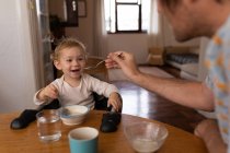 Front view close up of a young Caucasian father feeding his baby with a spoon — Stock Photo