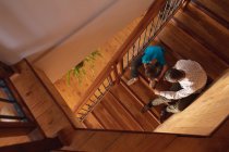 Vue aérienne d'un homme caucasien d'âge moyen assis sur un escalier avec son fils pré-adolescent, le garçon attache les lacets — Photo de stock