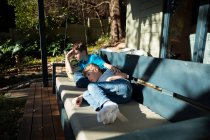 Vista laterale di due ragazzi caucasici pre-adolescenti sdraiati su una panchina in un giardino — Foto stock