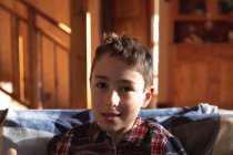 Portrait gros plan d'un pré adolescent garçon caucasien assis sur un canapé dans un salon à la maison, regardant à la caméra — Photo de stock
