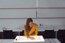 Вид спереди на молодую кавказскую студентку, работающую над дизайнерским рисунком на светофоре в студии колледжа моды — стоковое фото