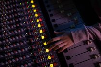 Overhead view of the hand of female sound engineer operating a mixing desk in a recording studio — Stock Photo