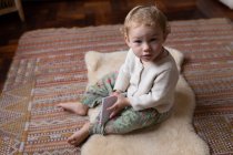 Портрет кавказького малюка, що сидить на підлозі і тримає записник з босоніж. — стокове фото