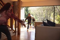 Visão traseira de uma mulher caucasiana de meia-idade cumprimentando seus dois filhos pré-adolescentes retornando para casa — Fotografia de Stock