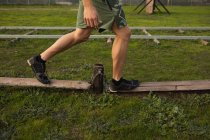 Vista lateral seção baixa do homem andando ao longo de postes de madeira em um ginásio ao ar livre durante uma sessão de treinamento de bootcamp — Fotografia de Stock