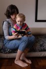 Vista frontale da vicino di una giovane madre caucasica e del suo bambino utilizzando uno smartphone — Foto stock