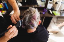 Vue arrière gros plan d'un coiffeur masculin caucasien d'âge moyen et d'une jeune femme caucasienne ayant les cheveux colorés dans un salon de coiffure — Photo de stock