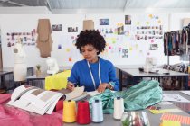 Frontansicht einer jungen Modestudentin mit gemischter Rasse, die in einem Atelier der Modehochschule an einem Design arbeitet — Stockfoto