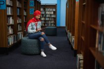 Visão lateral de uma jovem estudante asiática vestindo um turbante usando um computador tablet e estudando em uma biblioteca — Fotografia de Stock