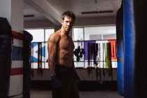 Retrato de un joven boxeador caucásico en un gimnasio de boxeo mirando a la cámara - foto de stock