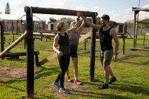 Front view of two young Caucasian women and a young Caucasian man high fiving at an outdoor gym during a bootcamp training session — Stock Photo