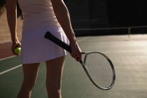 Вид ззаду крупним планом жінка грає в теніс в сонячний день, тримаючи ракетку і м'яч — стокове фото