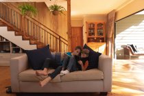 Vista frontale di due ragazzi caucasici pre-adolescenti sdraiati su un divano e che utilizzano tablet in salotto — Foto stock