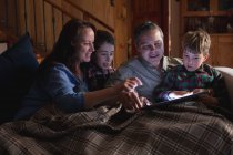 Nahaufnahme eines kaukasischen Mannes und einer kaukasischen Frau mittleren Alters, die zu Hause mit ihren beiden vorpubertären Söhnen einen Tablet-Computer benutzen — Stockfoto