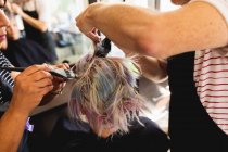 Visão traseira close-up de um cabeleireiro masculino caucasiano de meia-idade, uma cabeleireira mista de meia-idade e uma jovem mulher caucasiana com o cabelo colorido em um salão de cabeleireiro — Fotografia de Stock