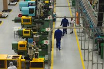Visão de alto ângulo dos trabalhadores da fábrica interagindo e andando por fileiras de máquinas em um armazém em uma fábrica de processamento — Fotografia de Stock