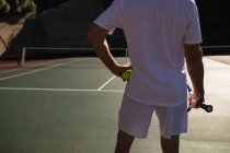 Задний план человека, играющего в теннис в солнечный день, держащего ракетку и мяч — стоковое фото