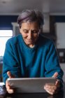 Vista frontal de cerca de una mujer mayor caucásica en una cocina usando una tableta - foto de stock