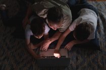 Vista aerea di un uomo caucasico di mezza età e dei suoi figli adolescenti che usano un computer portatile in un salotto — Foto stock