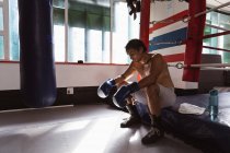 Вид збоку крупним планом молодий змішаної раси чоловічий боксер, що сидить у боксерському кільці — стокове фото