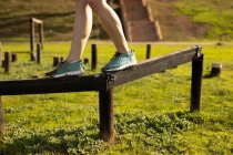 Side view low section of woman walking on a beam at an outdoor gym during a bootcamp training session — Stock Photo