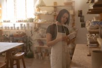 Вид збоку молоді кавказька жіноча Поттер оглядає блюдо в гончарній майстерні, проглядається через скло — стокове фото