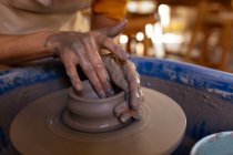 Nahaufnahme der Hände von Töpferinnen, die in einem Töpferatelier feuchten Ton zu einem Topf auf einer Töpferscheibe formen — Stockfoto